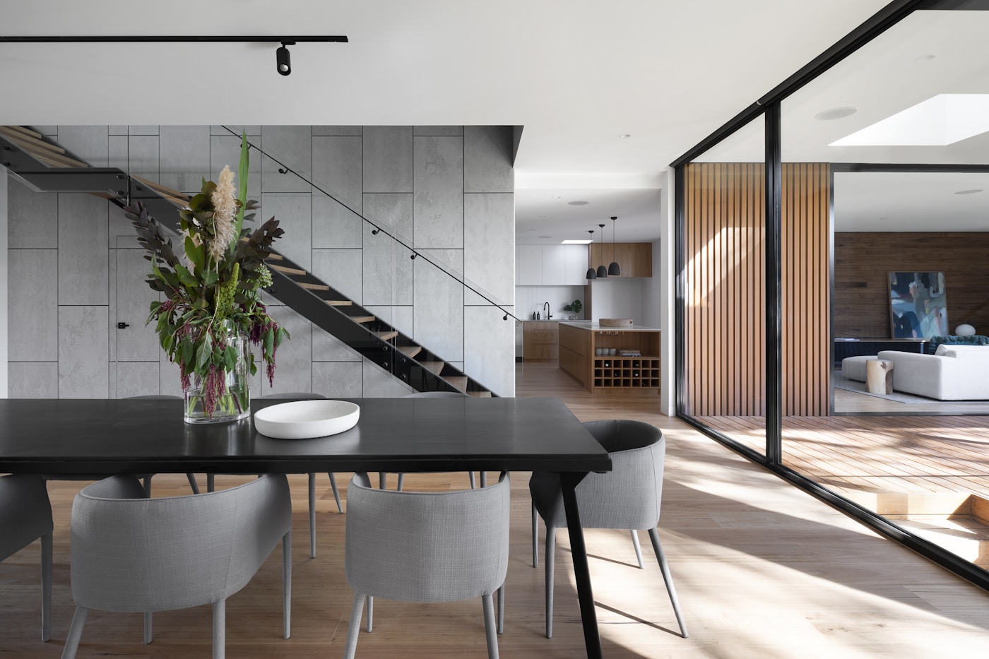 Modern dining space with sculptural chairs, stone walls, and floor-to-ceiling glass